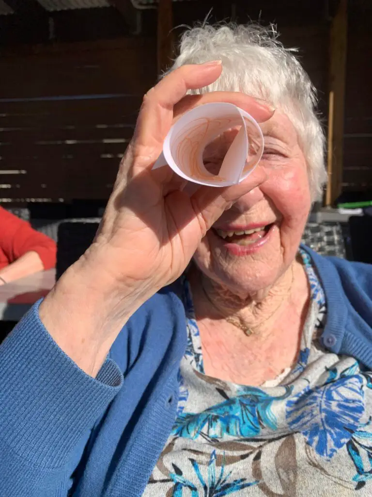 Elderly lady using rolled paper as monocular
