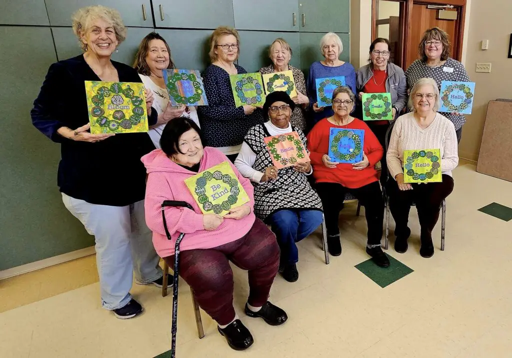 elder women in aged care holding their paintings