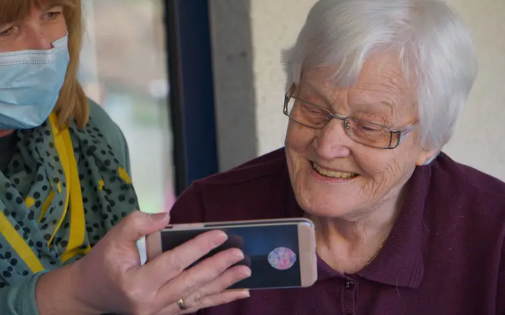 staff helping baby boomer elder with smartphone